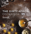 Book cover of the Dirty Apron Cookbook. The cover shows a countertop with some pieces of freshly made ravioli and a bowl of egg wash.